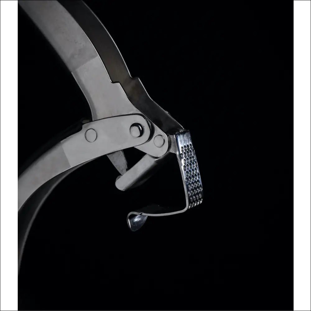 Close-up of a steel garlic crusher with a patterned pressing plate.