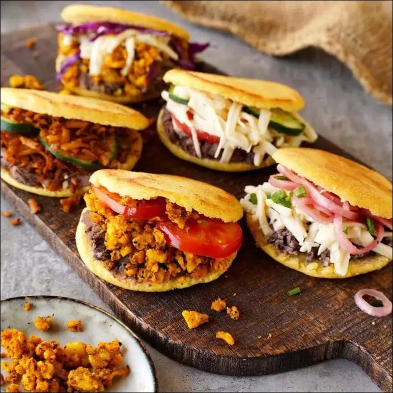 Assorted toasty arepas on a wooden board made with the Smart ArepaPro Maker