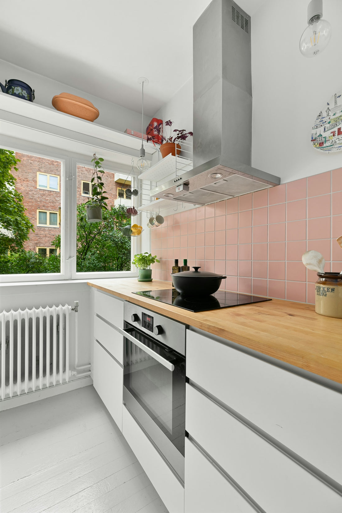 A kitchen with pink tiles and white cabinets