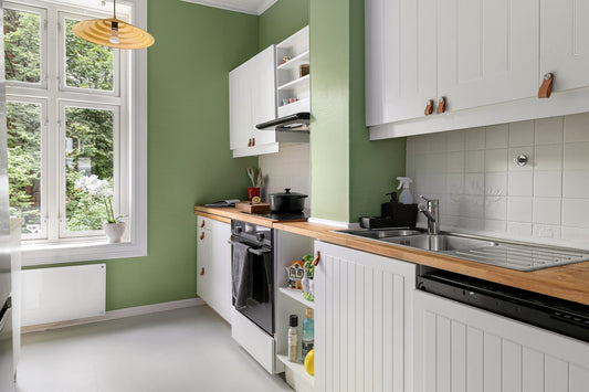A kitchen with green walls and white cabinets