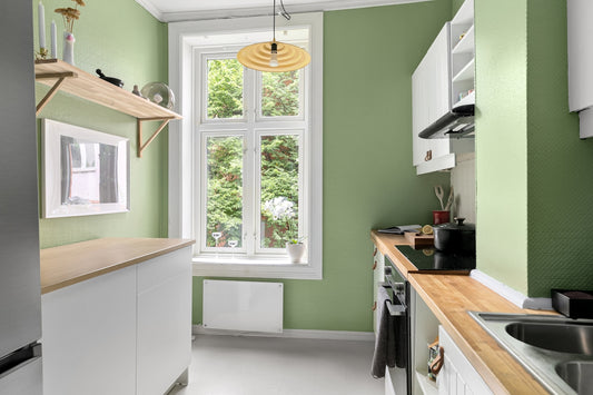 A kitchen with green walls and white cabinets