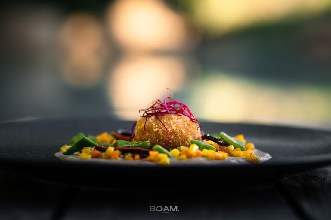 A black plate topped with food on top of a wooden table