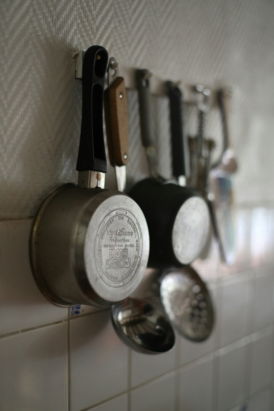 Pots and utensils hanging on a kitchen wall.