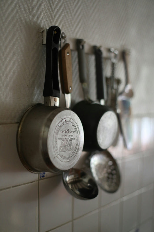 Pots and utensils hanging on a kitchen wall.
