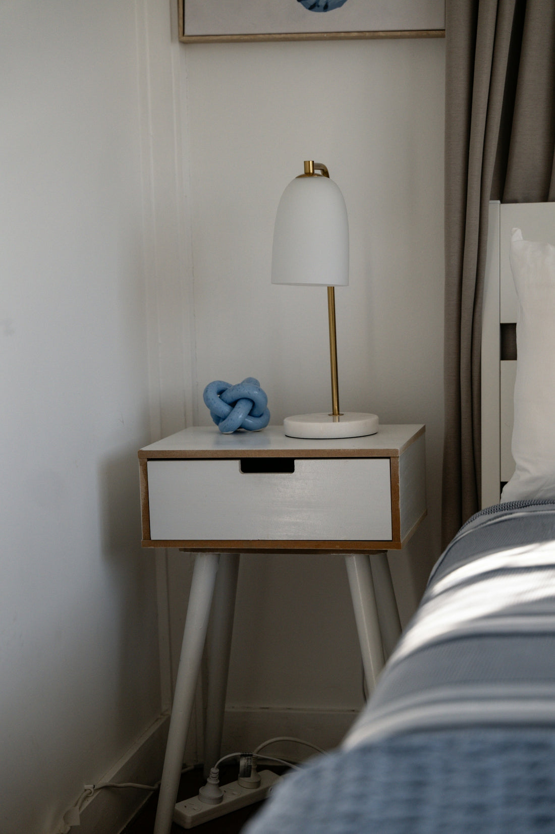A modern bedside table with a lamp and decor.