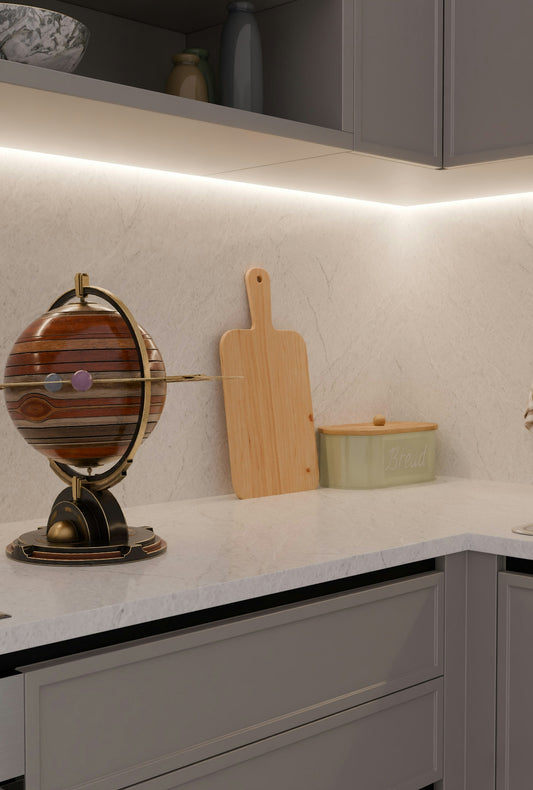 Decorative globe, cutting board, and bread bin on kitchen counter.