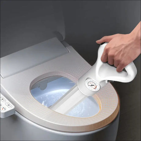 White clog buster tool clearing a toilet drain with built-in pressure gauge.