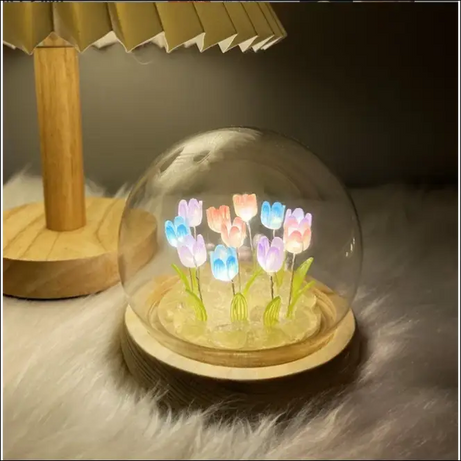 Illuminated tulips inside glass dome, decorative flowers on wooden base.